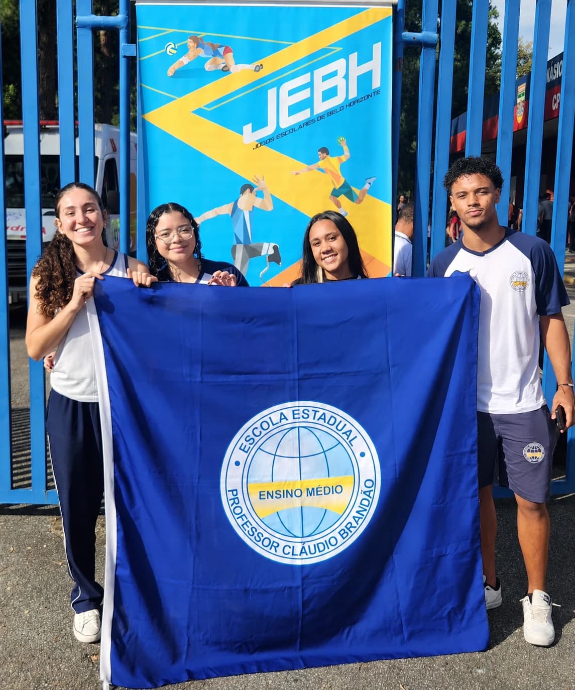 Atletas com a bandeira da escola diante do painel dos Jogos Escolares de Belo Horizonte