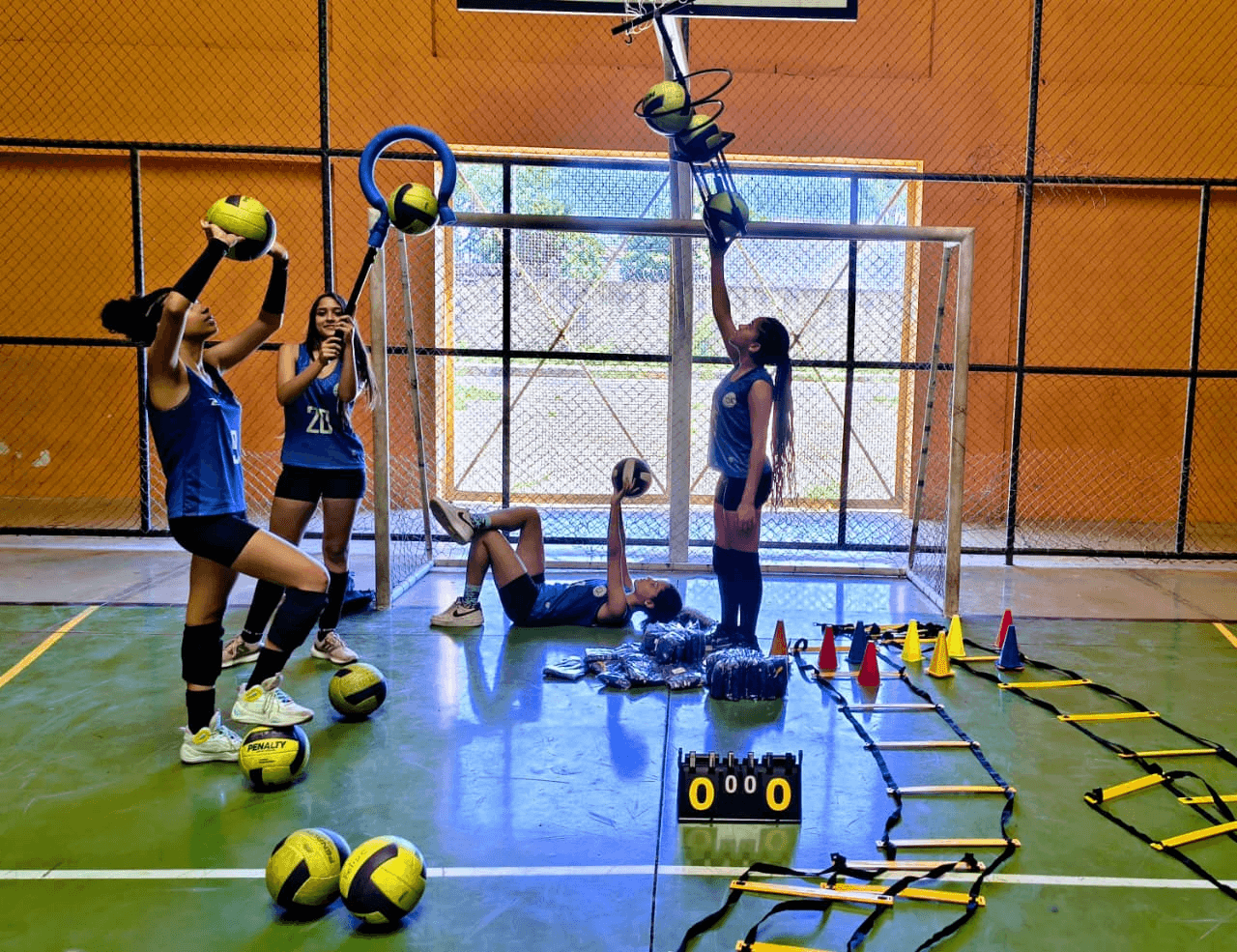 Atletas realizando atividades esportivas com bolas e materiais em uma quadra coberta