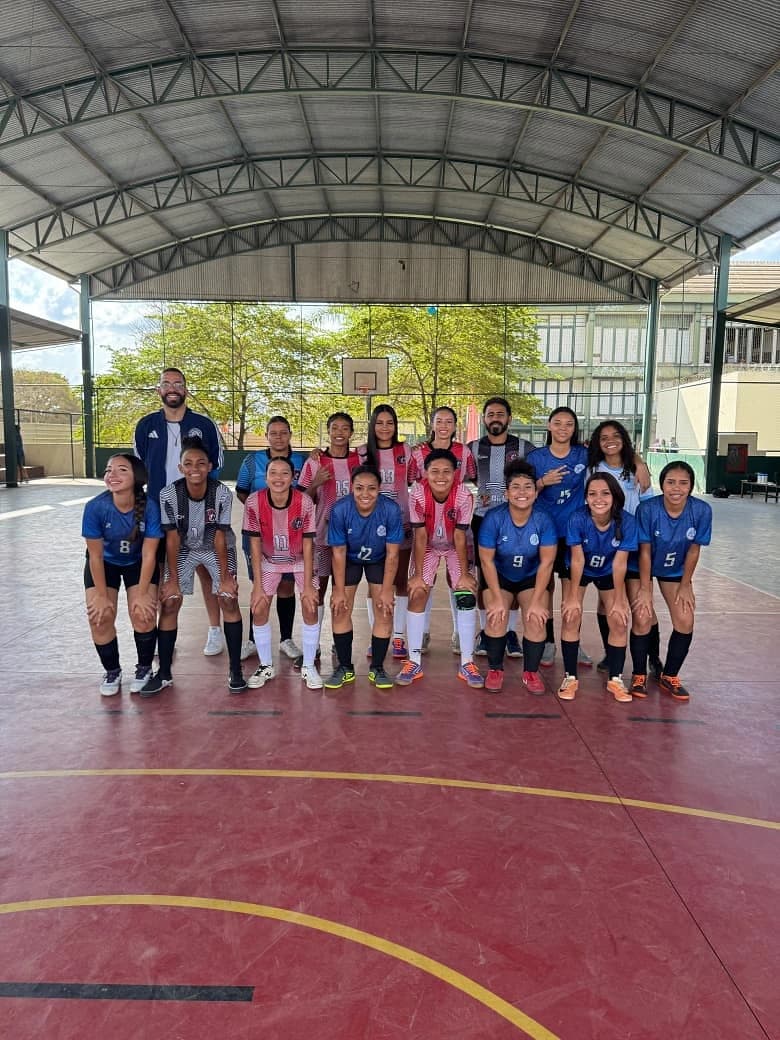 Atletas do Futsal feminino e da equipe adversária posadas na quadra coberta
