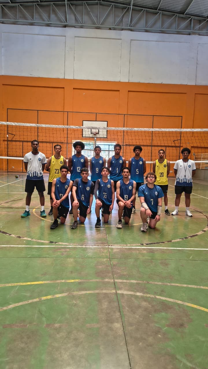 Equipe de Voleibol Masculino formada diante da rede após a competição
